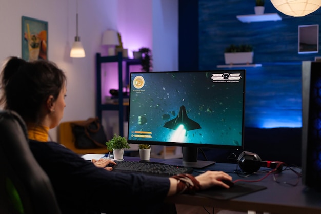 Person using keyboard and mouse to play video games on computer. Gamer playing online game in front of monitor with control console and mousepad on desk. Modern player with gaming equipment