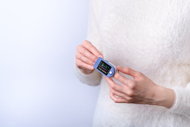 Person using pulse oximeter device on finger, healthcare monitoring concept