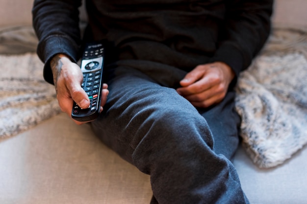 Photo person using remote controller while sitting in couch