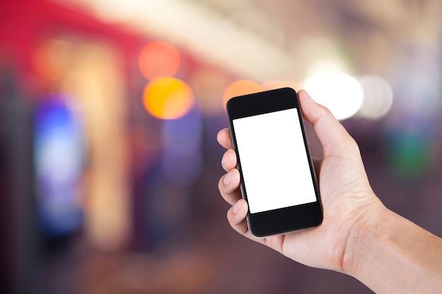 Person using smartphone white screen holder on hand with  blurred background of people walking in electrical train station.