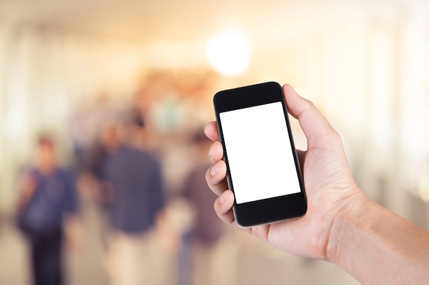 Person using smartphone white screen holder on hand with  many people walking on skywalk in the big city.