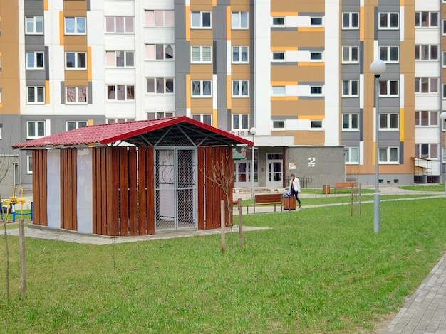 A person walking in front of a building with a red roof.