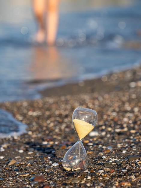 Person walking near Hourglass on the beach at the seashore