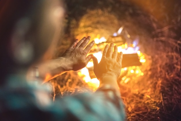 The person warming hands above the bonfire. evening night time