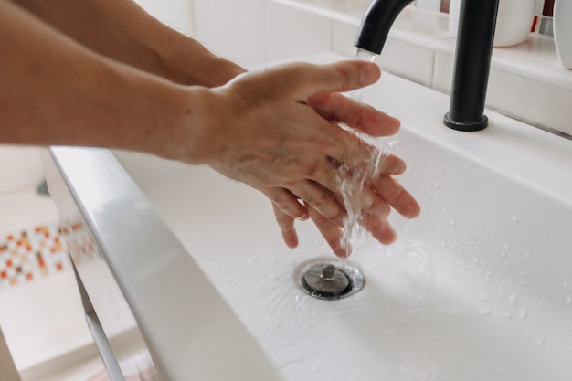 Person wash hands in the bathroom concept of health and protection