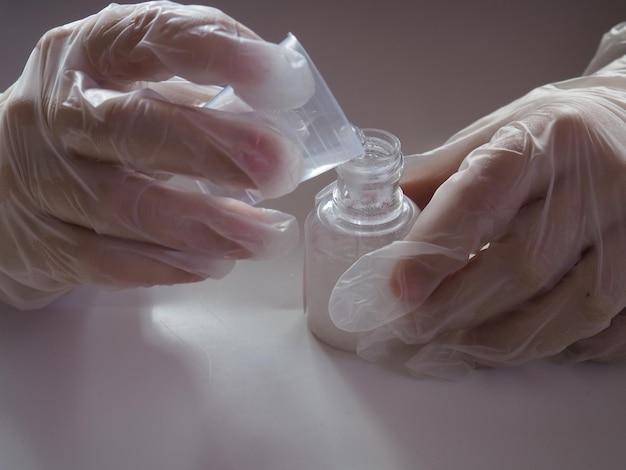 A person wearing a glove is applying a bottle of nail polish.