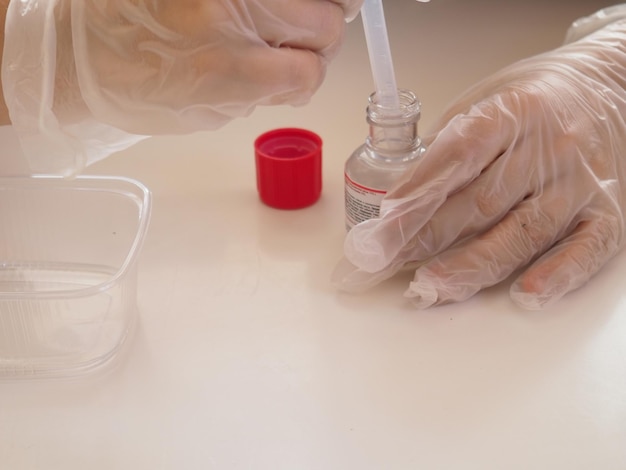 A person wearing gloves is filling a tube with a liquid.