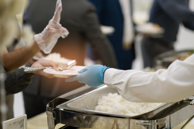 手袋をはめて食べ物をすくい、ケータリング、夕食の時間、コロナウイルス病を予防する人（covid 19）