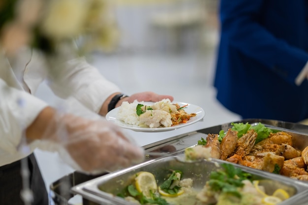 Foto una persona che indossa guanti che raccoglie cibo per la ristorazione durante la cena previene la malattia di coronavirus covid 19xa