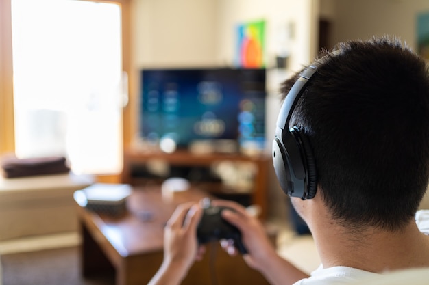 Person wearing headphones and playing video games on tv