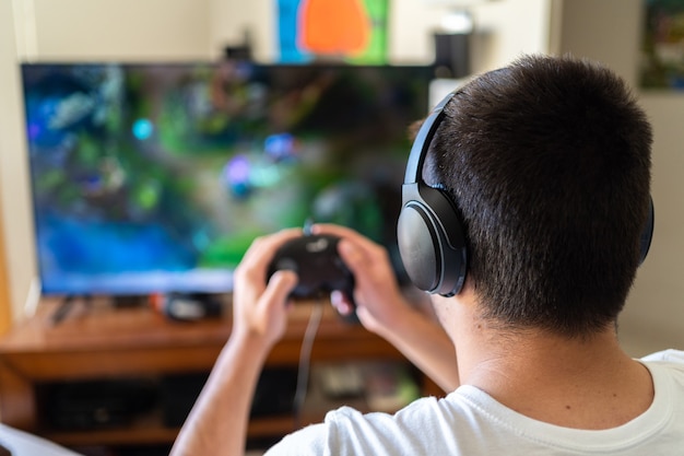 Person wearing headphones and playing video games on TV