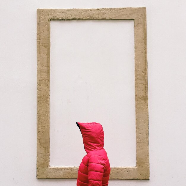 Photo person wearing red hood against wall