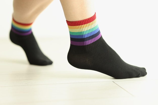 Persona che indossa calze con bandiera lgbtq ornata su pavimento piastrellato accessorio di moda con bordo arcobaleno