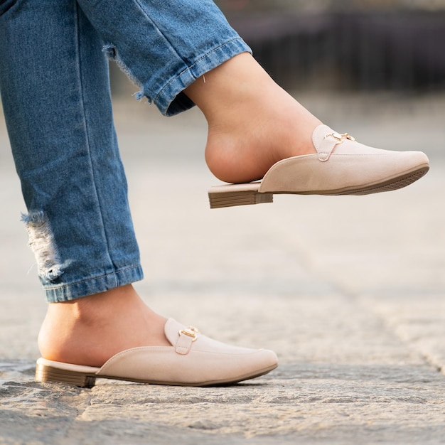Of a person wearing stylish and beautiful beige colored mule shoes