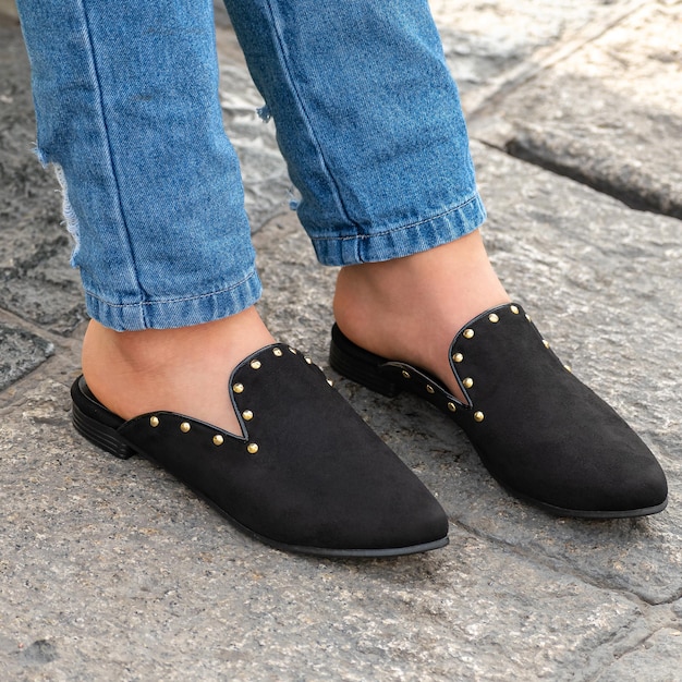 Of a person wearing stylish and beautiful black colored mule shoes