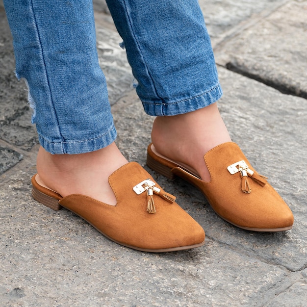Of a person wearing stylish and beautiful brown colored mule shoes
