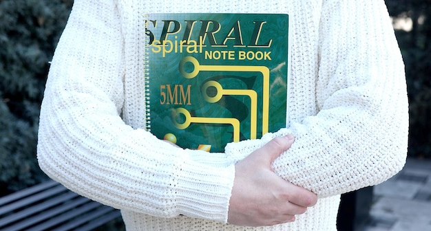 A person wearing a white sweater with a note book on it.