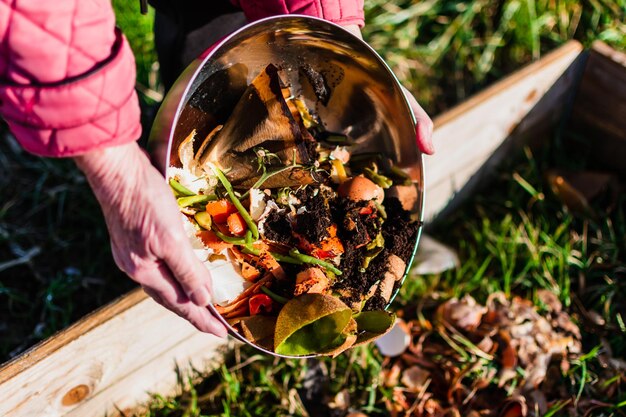 Person who put in a composter some kitchen waste like vegetables fruits eggshell coffee grounds in order to sort and make bio fertilizer