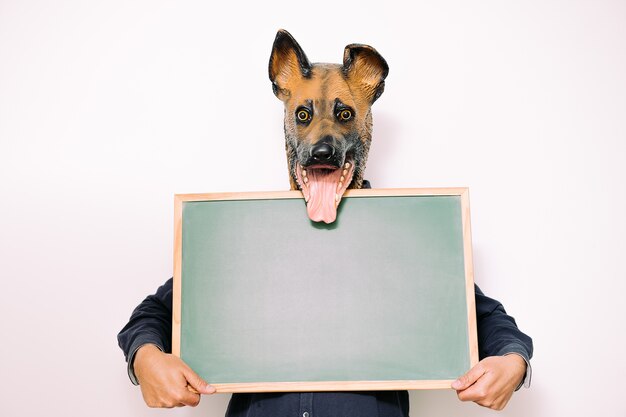 Person with dog mask holds a blank blackboard