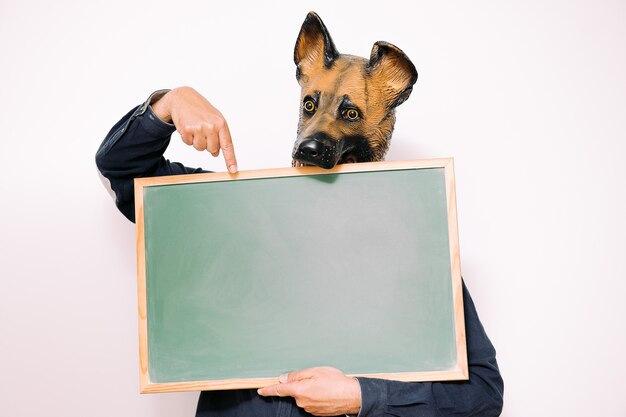 Фото Человек в маске собаки указывает на чистый лист