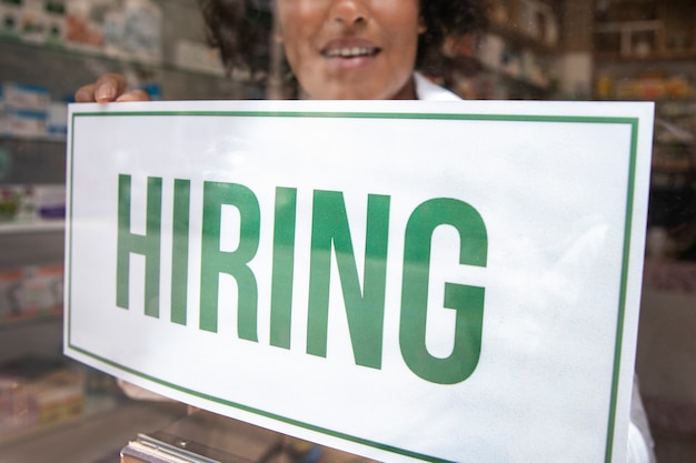 Person with hiring sign by the window