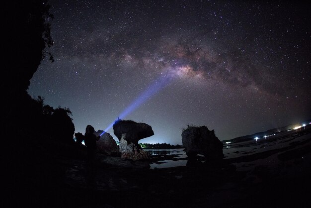 Foto persona con apparecchiature di illuminazione illuminate sulla spiaggia di notte