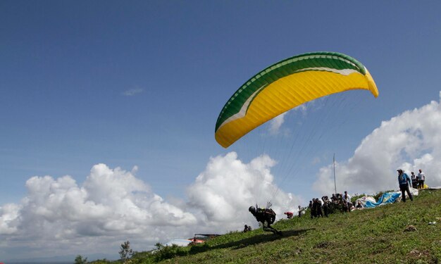 Person with parachute on green mountain
