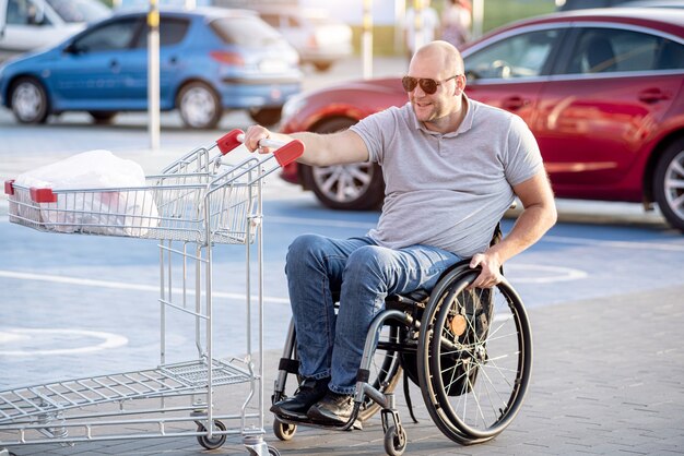 Person with a physical disability pushing cart in front of himself at supermarket parking