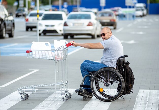 Person with a physical disability pushing cart in front of himself at supermarket parking