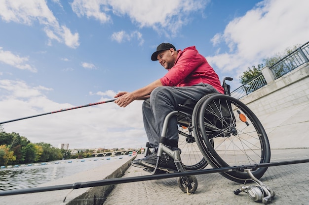 Лицо с ограниченными физическими возможностями, использующее инвалидную коляску для ловли рыбы с рыбацкого пирса