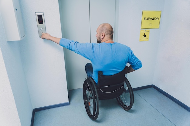 Человек с ограниченными физическими возможностями, использующий инвалидную коляску, пользуется лифтом в здании