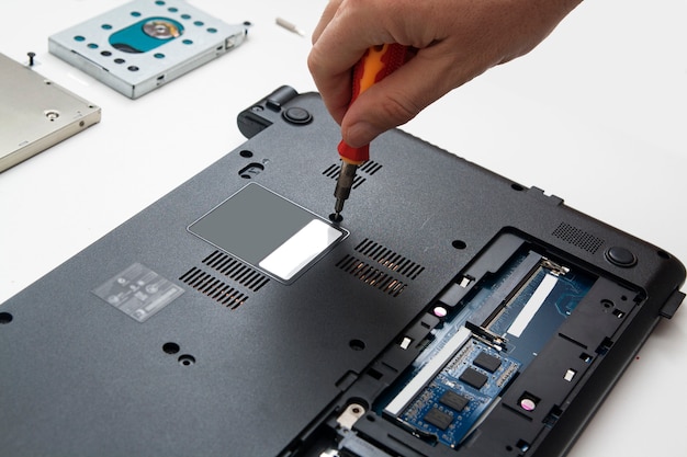 Person with a screwdriver disassembles the laptop case for parts to replace parts and repair