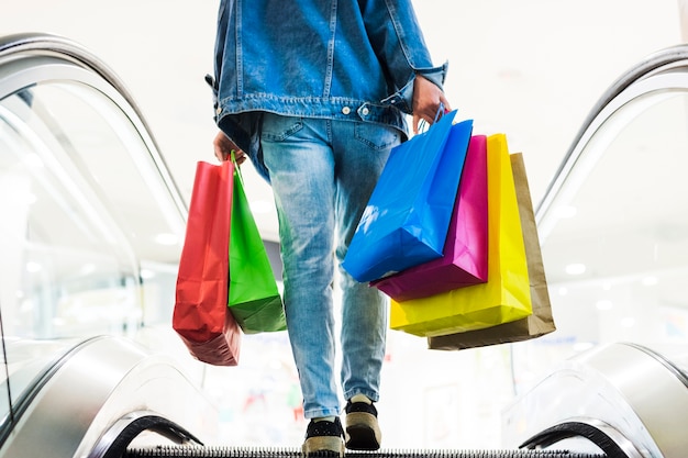 Photo person with shopping bags on the escalator