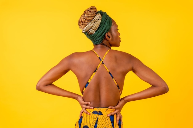 A person woman of black ethnicity with traditional costume on\
yellow background model with a bare back