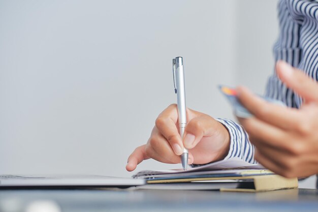 Foto una persona che scrive su un blocco note con una penna.