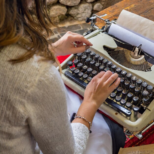 Photo person writing on vintage typewriter with old paper