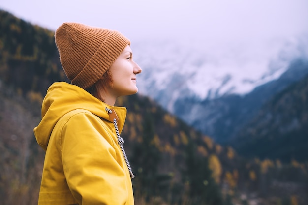 person in yellow jacket looking at mountains Adventure travel Autumn or winter time in Europe