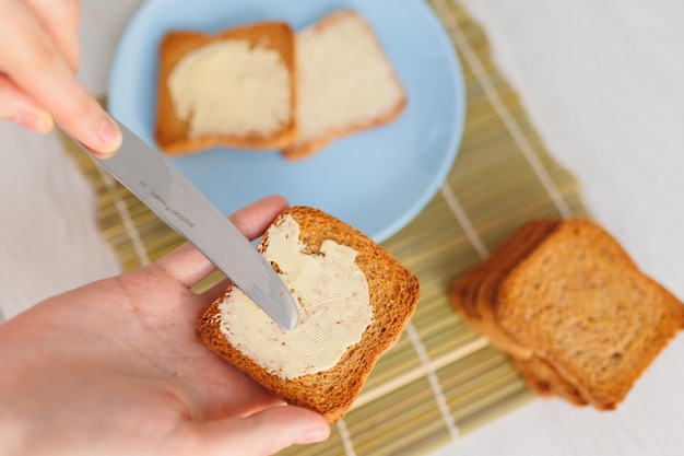 A person39s hands delicately spreading butter on a piece of freshly sliced bread