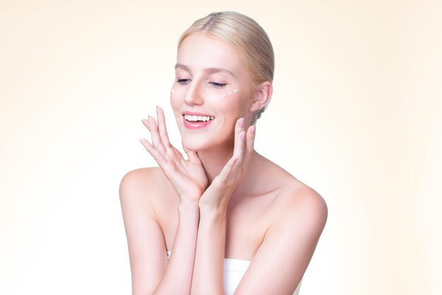 Personable woman applying moisturizer cream on her face for perfect skin