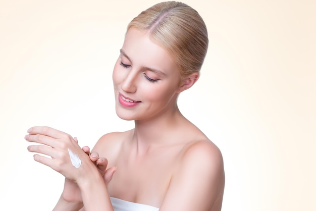 Personable woman applying moisturizer cream on her han in isolated background