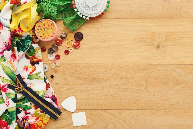 Personal creative fashion designer workspace. Top view on fabric and various tools and accessories on wooden table with copy space