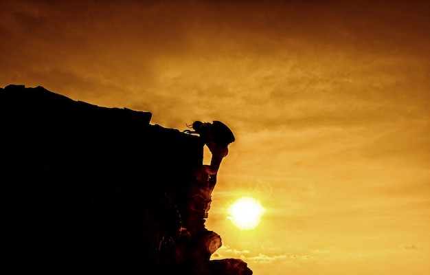 Personal development. Business success and goal concept. Silhouette climber on the cliff.