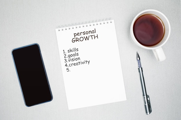 Personal development concept Top view of notebook smartphone cup with tea on desk