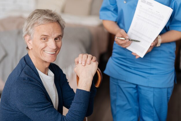 Personal helper. Smart positive qualified doctor explaining her client all the terms of her work while he wanting her taking care of him