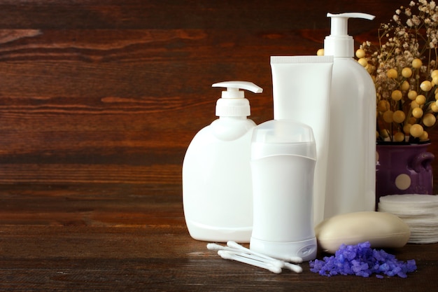 Personal hygiene items with decorative sprigs on a brown wooden background