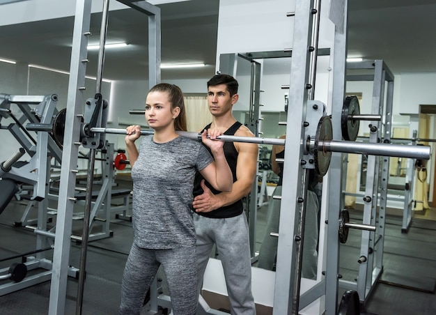 Personal instructor helping woman to lift a dumbbell