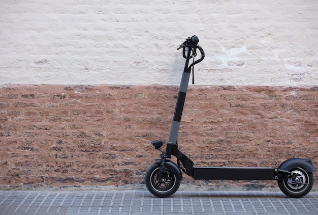 Электрический скутер для личного передвижения, припаркованный в городе с деревенской кирпичной стеной b