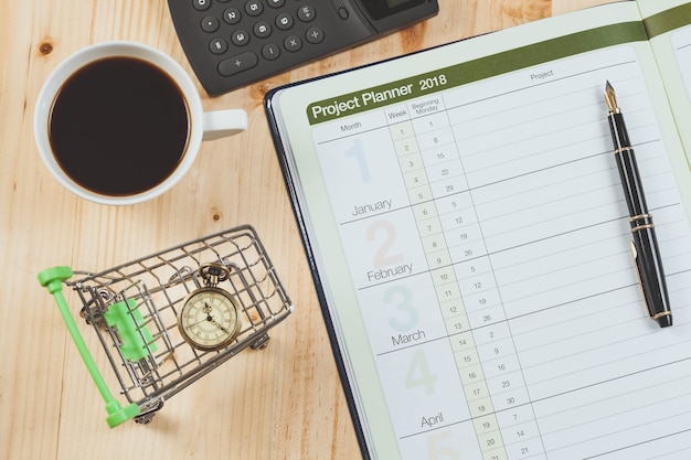 Photo personal project planner with fountain pen and hot coffee on wood table.