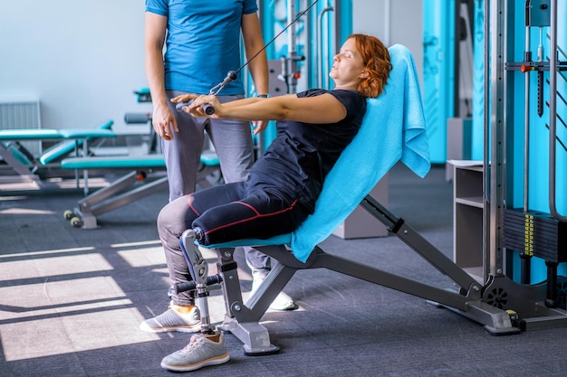 Personal trainer assisting woman with disabilities in her workout. Sports Rehab Centre with physiotherapists and patients working together towards healing.