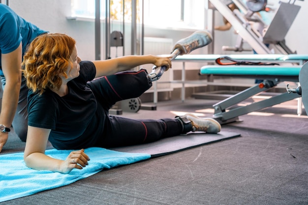 Personal trainer assisting woman with disabilities in her workout. Sports Rehab Centre with physiotherapists and patients working together towards healing.